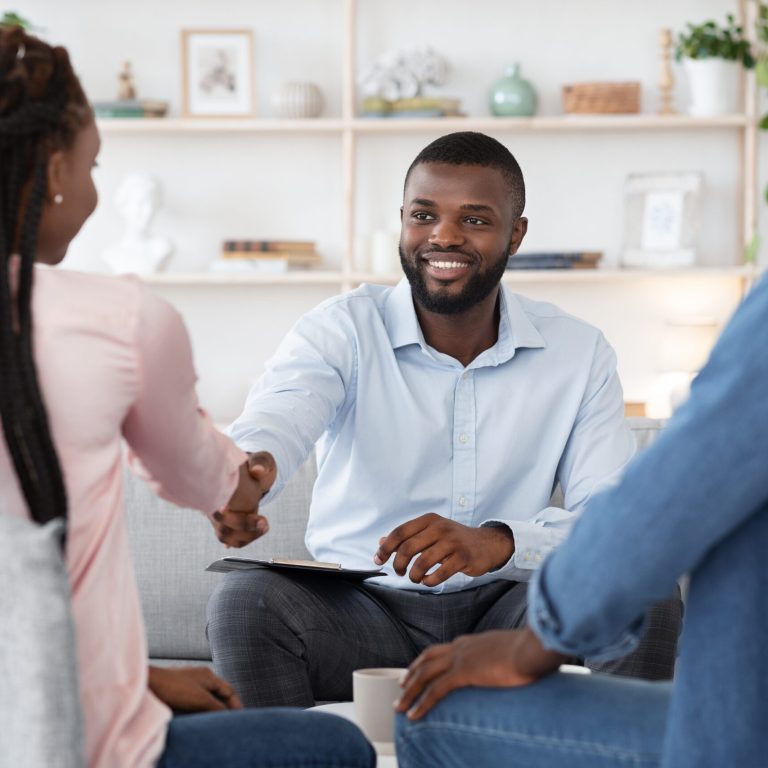 Family Counselor Shaking Hands With Happy Black Couple After Successful Therapy, Selective Focus At Therapist